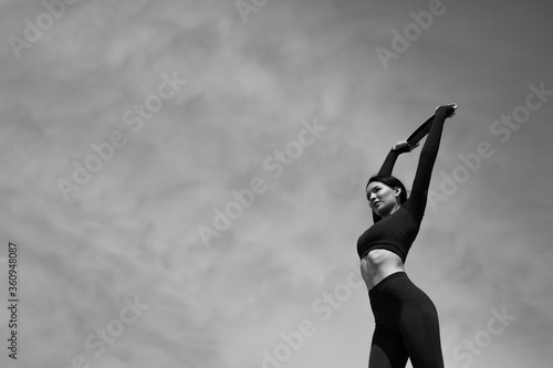 Black and white photo of the girl doing exercises to warm up the muscles by using elastic bands for exercise.