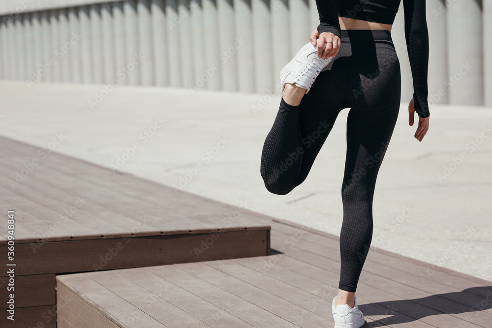 Female feet in black athletic tights while doing exercises on