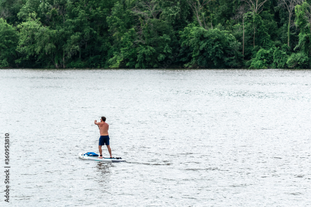 Tourist paddle boarding on the Potomac River with colorful paddle board in a sunny summer day near Washington, D.C. and Virginia. Tourist paddle boarding on the Potomac River with colorful paddle board in a sunny summer day near Washington, D.C. and Virginia.