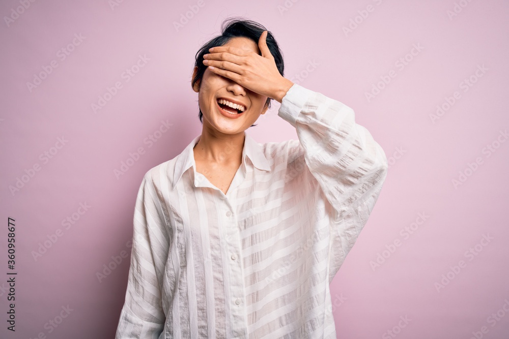 Young beautiful asian girl wearing casual shirt standing over isolated pink background smiling and laughing with hand on face covering eyes for surprise. Blind concept. Young beautiful asian girl wearing casual shirt standing over isolated pink background smiling and laughing with hand on face covering eyes for surprise. Blind concept.