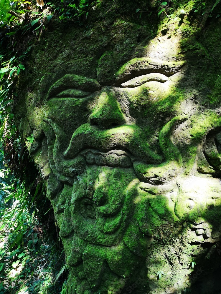Stone sculpture depicting a face at Kanto Lampo waterfall near Ubud, Indonesia