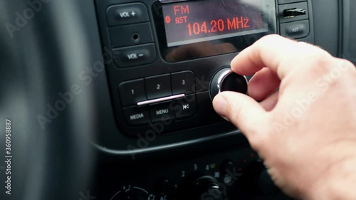 Radio and music in the car. Driver tunes car radio to media radio station frequency 