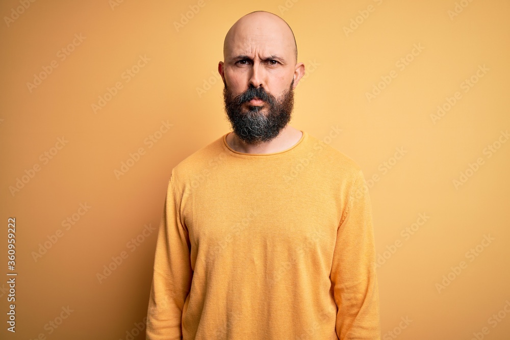 Handsome bald man with beard wearing casual sweater standing over yellow background depressed and worry for distress, crying angry and afraid. Sad expression. Handsome bald man with beard wearing casual sweater standing over yellow background depressed and worry for distress, crying angry and afraid. Sad expression.