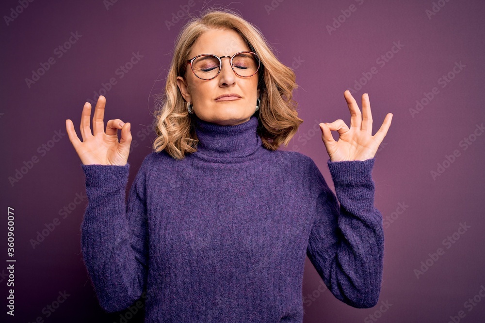 Middle age beautiful blonde woman wearing casual purple turtleneck sweater and glasses relax and smiling with eyes closed doing meditation gesture with fingers. Yoga concept. Middle age beautiful blonde woman wearing casual purple turtleneck sweater and glasses relax and smiling with eyes closed doing meditation gesture with fingers. Yoga concept.
