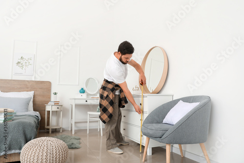 Male carpenter using tape m...