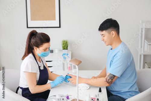 Manicure master working with male client in beauty salon