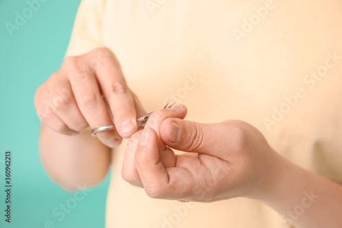 Asian man doing manicure on color background, closeup