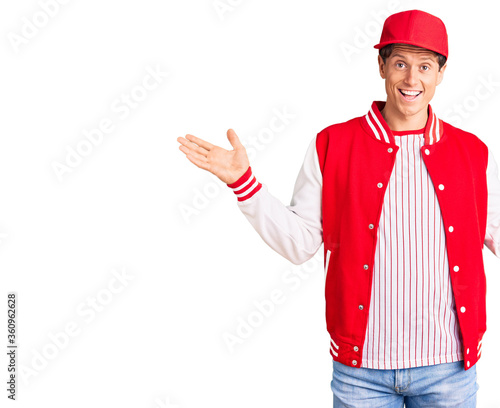 Young handsome man wearing baseball uniform holding golve and ball celebrating victory with happy smile and winner expression with raised hands photo