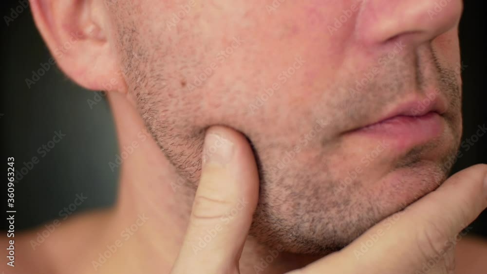 Unshaven man examines his unshaven face and stubble close up and plans to shave his bristles Unshaven man examines his unshaven face and stubble close up and plans to shave his bristles