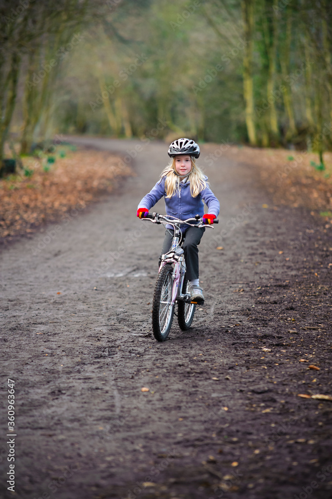 A young girl rides a bike along a country track towards the camera A young girl rides a bike along a country track towards the camera