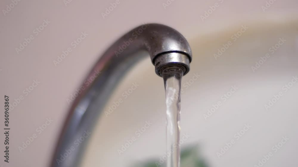 Water flows pouring from an old faucet. Saving fresh water and natural resources Water flows pouring from an old faucet. Saving fresh water and natural resources