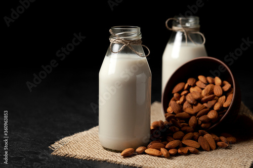 almond milk in bottles with nuts on a dark table, a variety of dairy products without sugar and lactose, a vegetarian drink
