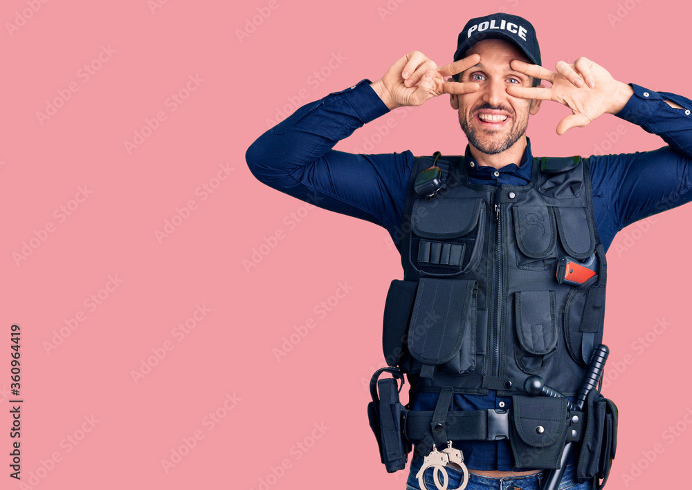 Young handsome man wearing police uniform doing peace symbol with fingers over face, smiling cheerful showing victory Young handsome man wearing police uniform doing peace symbol with fingers over face, smiling cheerful showing victory