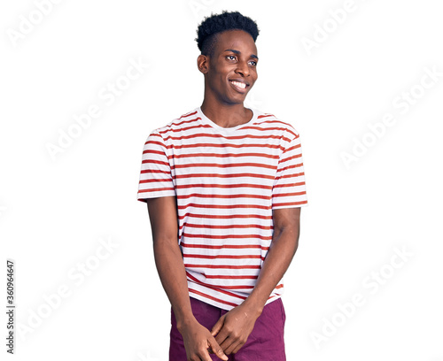 Young african american man wearing casual clothes looking away to side with smile on face, natural expression. laughing confident.
