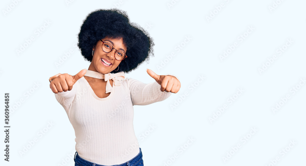 Young african american girl wearing casual clothes and glasses approving doing positive gesture with hand, thumbs up smiling and happy for success. winner gesture. Young african american girl wearing casual clothes and glasses approving doing positive gesture with hand, thumbs up smiling and happy for success. winner gesture.