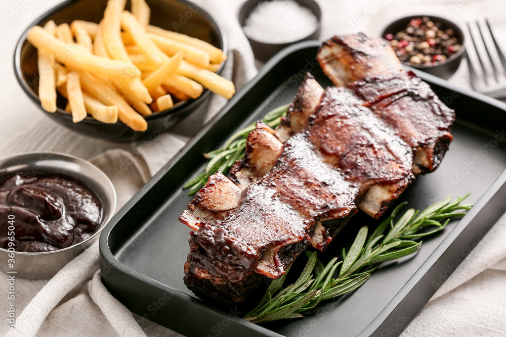 Tasty beef short ribs with sauce and french fries on table
