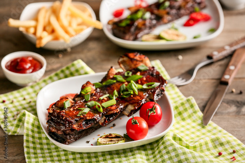 Tasty beef short ribs with vegetables on table