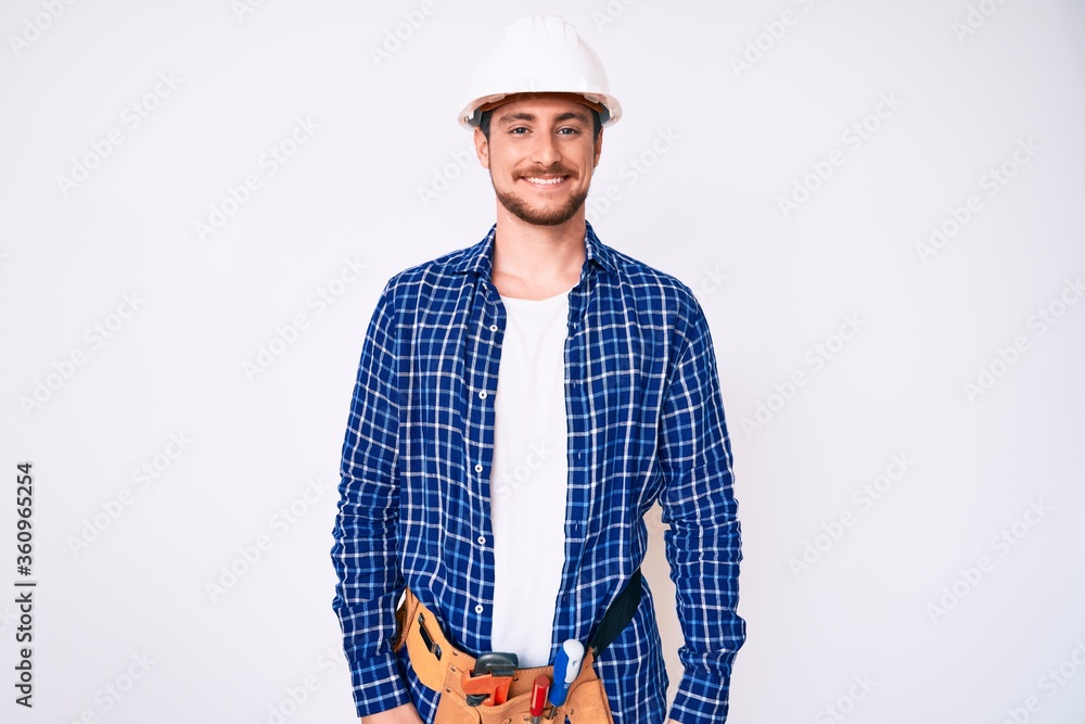 Young handsome man weaing handyman uniform looking positive and happy standing and smiling with a confident smile showing teeth Young handsome man weaing handyman uniform looking positive and happy standing and smiling with a confident smile showing teeth