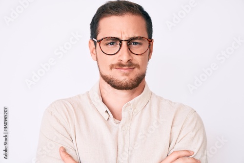 Young handsome man wearing casual clothes and glasses skeptic and nervous, disapproving expression on face with crossed arms. negative person. © Krakenimages.com