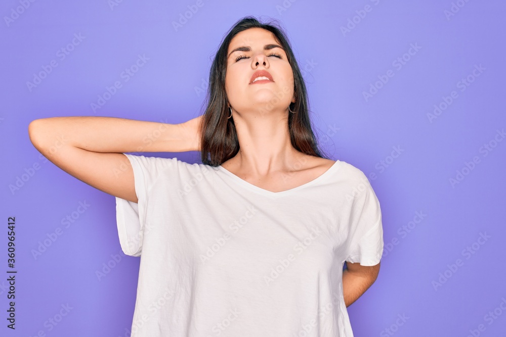 Obraz premium Young beautiful brunette woman wearing casual white t-shirt over purple background Suffering of neck ache injury, touching neck with hand, muscular pain