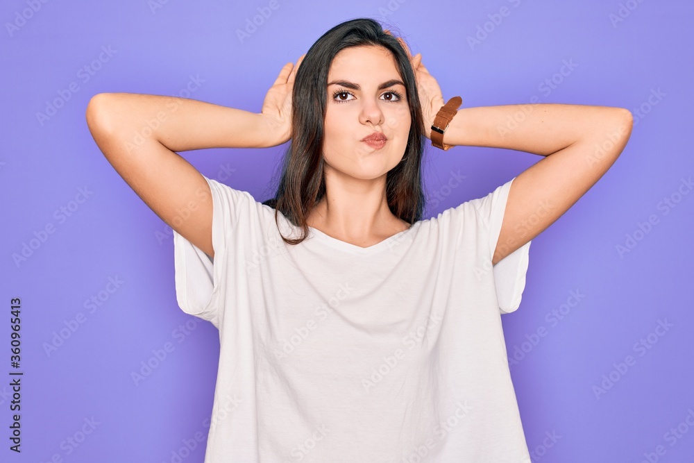 Young beautiful brunette woman wearing casual white t-shirt over purple background Doing bunny ears gesture with hands palms looking cynical and skeptical. Easter rabbit concept. Young beautiful brunette woman wearing casual white t-shirt over purple background Doing bunny ears gesture with hands palms looking cynical and skeptical. Easter rabbit concept.