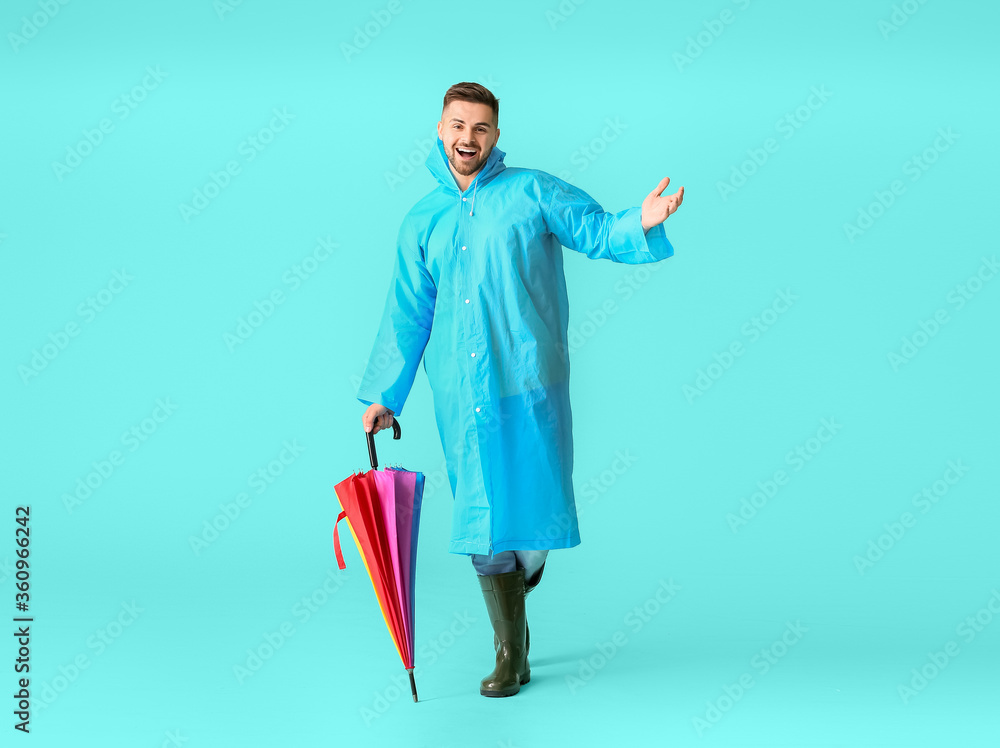 Young man in raincoat and with umbrella on color background Young man in raincoat and with umbrella on color background