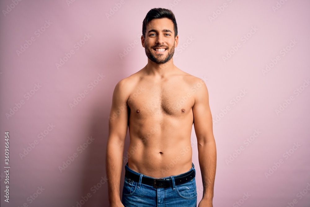 Young handsome strong man with beard shirtless standing over isolated pink background with a happy and cool smile on face. Lucky person.
