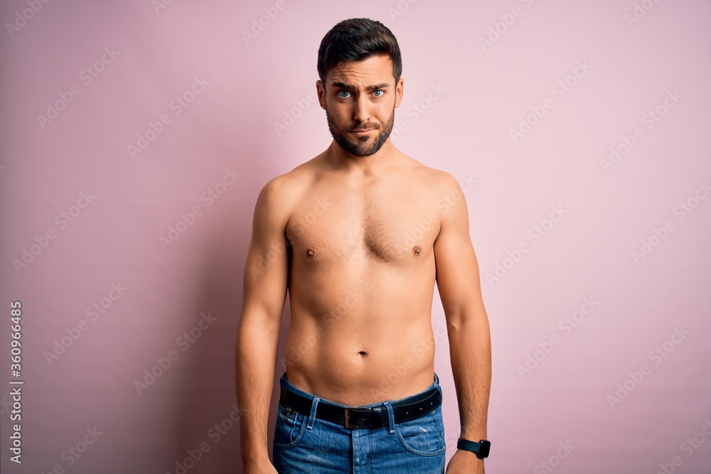 Young handsome strong man with beard shirtless standing over isolated pink background skeptic and nervous, frowning upset because of problem. Negative person.