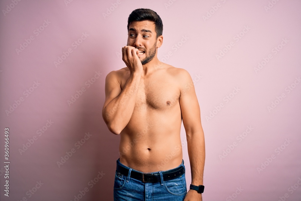 Young handsome strong man with beard shirtless standing over isolated pink background looking stressed and nervous with hands on mouth biting nails. Anxiety problem. Young handsome strong man with beard shirtless standing over isolated pink background looking stressed and nervous with hands on mouth biting nails. Anxiety problem.