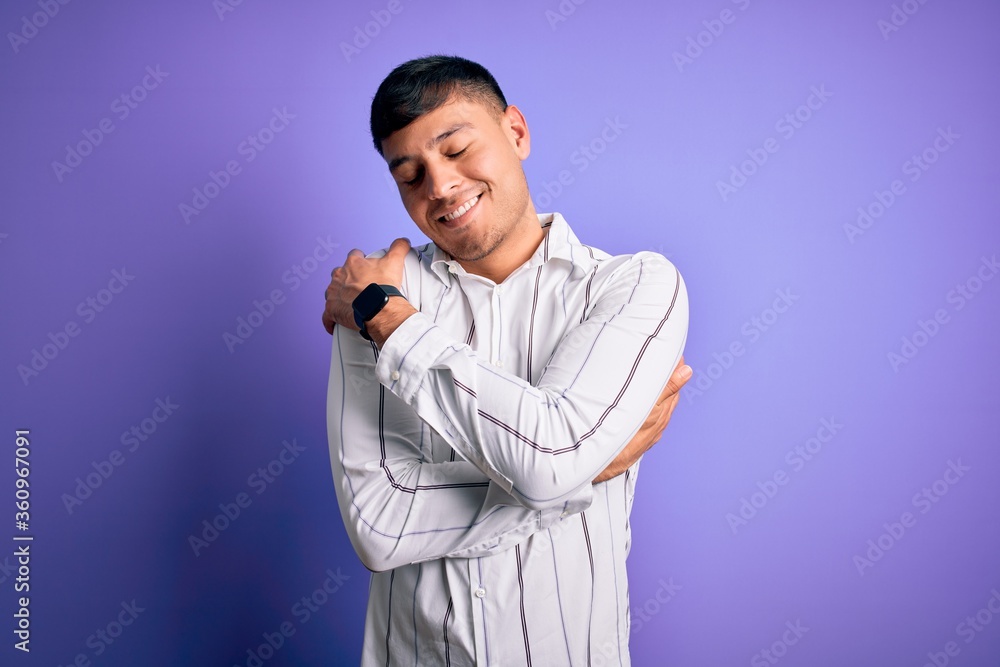 Young handsome hispanic man wearing elegant business shirt standing over purple background Hugging oneself happy and positive, smiling confident. Self love and self care Young handsome hispanic man wearing elegant business shirt standing over purple background Hugging oneself happy and positive, smiling confident. Self love and self care