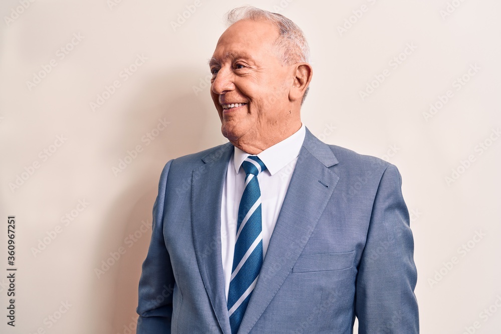 Senior handsome grey-haired businessman wearing elegant suit over white background looking to side, relax profile pose with natural face and confident smile. Senior handsome grey-haired businessman wearing elegant suit over white background looking to side, relax profile pose with natural face and confident smile.