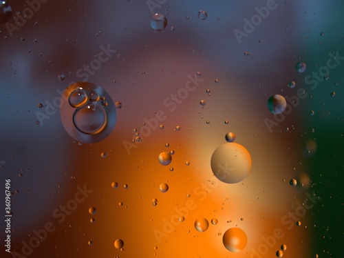 Closeup golden yellow bubbles oil in water with orange light , blurred abstract background, macro image ,droplets for card design