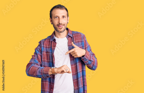 Young handsome man wearing casual clothes in hurry pointing to watch time, impatience, upset and angry for deadline delay