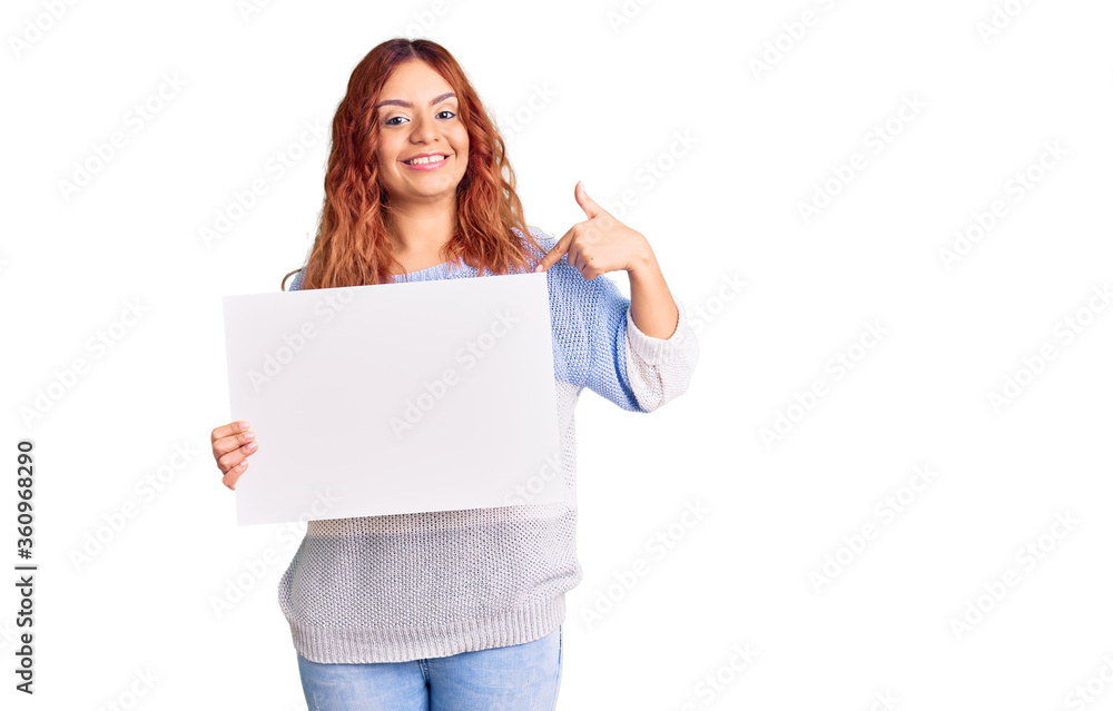 Young latin woman holding blank empty banner pointing finger to one self smiling happy and proud Young latin woman holding blank empty banner pointing finger to one self smiling happy and proud