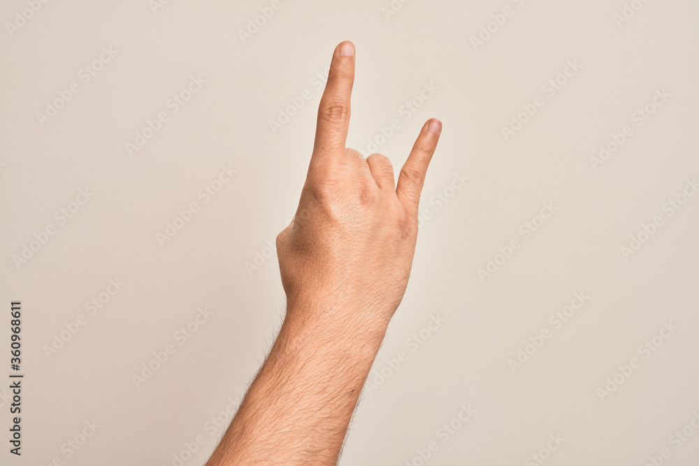 Hand of caucasian young man showing fingers over isolated white background gesturing rock and roll symbol, showing obscene horns gesture Hand of caucasian young man showing fingers over isolated white background gesturing rock and roll symbol, showing obscene horns gesture