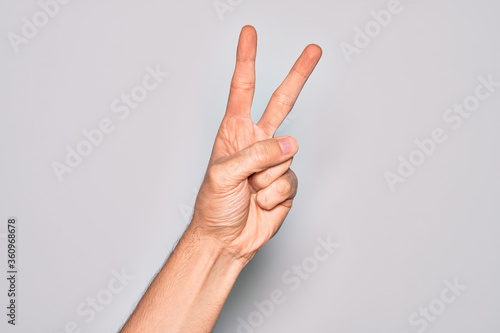 Hand of caucasian young man showing fingers over isolated white background counting number 2 showing two fingers, gesturing victory and winner symbol
