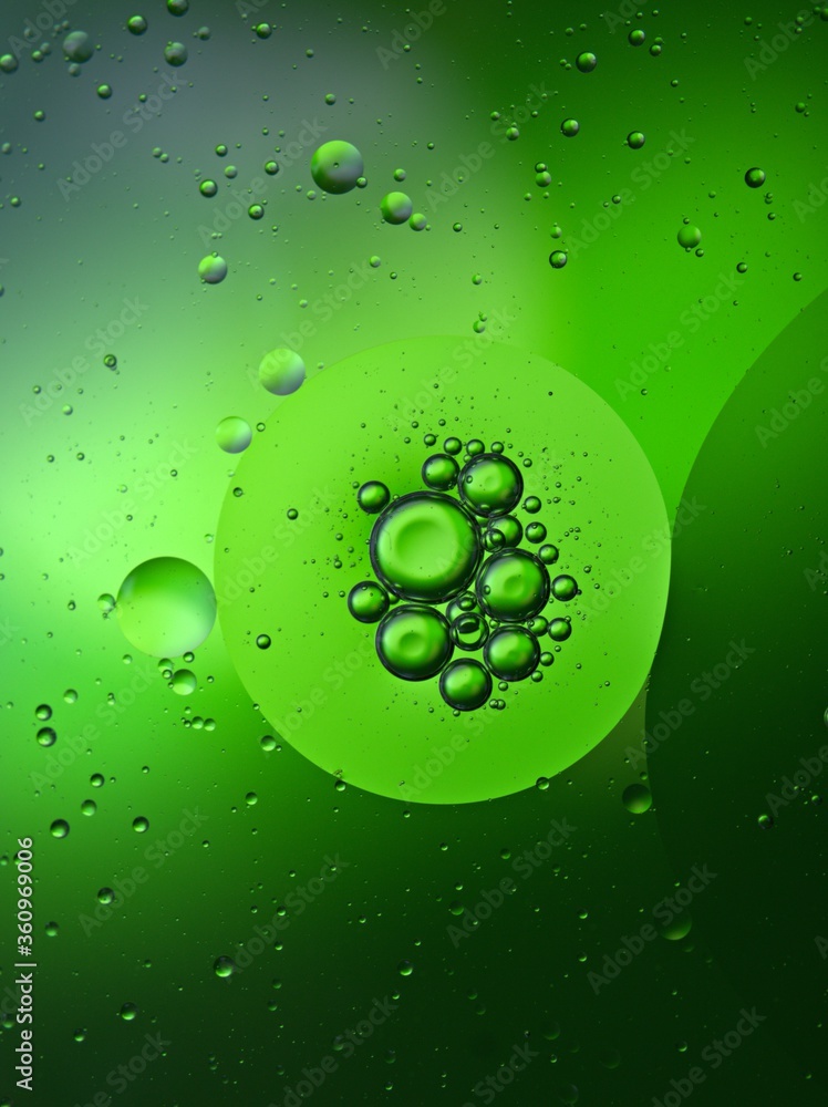Closeup bubbles oil in water with green blurred abstract background, macro image ,droplets for card design, sweet color	