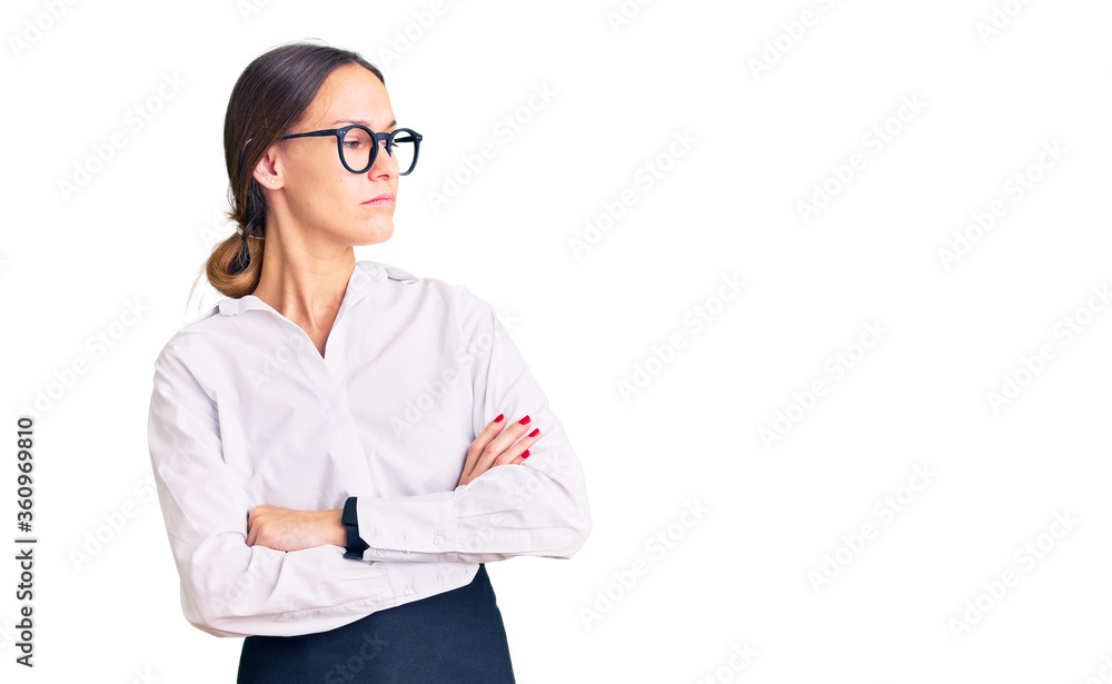 Beautiful brunette young woman wearing professional waitress apron looking to the side with arms crossed convinced and confident Beautiful brunette young woman wearing professional waitress apron looking to the side with arms crossed convinced and confident