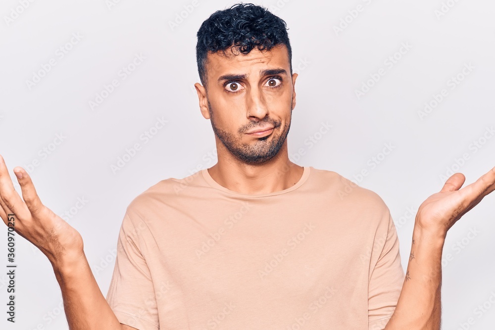 Young hispanic man wearing casual clothes clueless and confused with open arms, no idea and doubtful face. Young hispanic man wearing casual clothes clueless and confused with open arms, no idea and doubtful face.