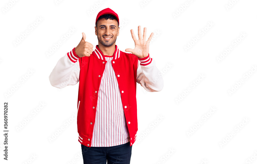 Young hispanic man wearing baseball uniform showing and pointing up with fingers number six while smiling confident and happy. Young hispanic man wearing baseball uniform showing and pointing up with fingers number six while smiling confident and happy.