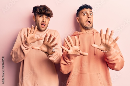 Fotografía Young gay couple wearing casual clothes afraid and terrified with fear expression stop gesture with hands, shouting in shock