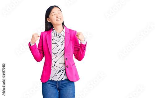 Young beautiful chinese woman wearing elegant clothes very happy and excited doing winner gesture with arms raised, smiling and screaming for success. celebration concept.