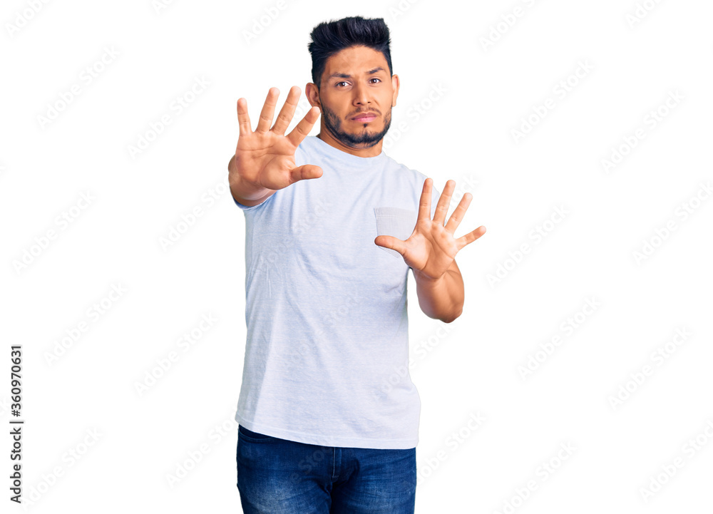 Handsome latin american young man wearing casual clothes afraid and terrified with fear expression stop gesture with hands, shouting in shock. panic concept. Handsome latin american young man wearing casual clothes afraid and terrified with fear expression stop gesture with hands, shouting in shock. panic concept.