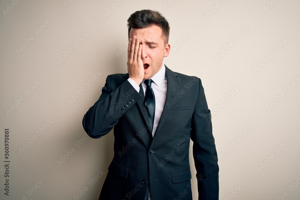 Young handsome business man wearing elegant suit and tie over isolated background Yawning tired covering half face, eye and mouth with hand. Face hurts in pain. Young handsome business man wearing elegant suit and tie over isolated background Yawning tired covering half face, eye and mouth with hand. Face hurts in pain.