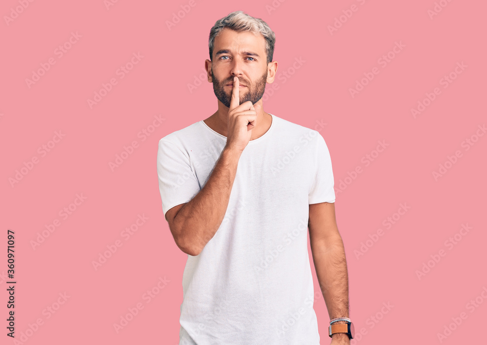 Young handsome blond man wearing casual t-shirt shouting and screaming loud to side with hand on mouth. communication concept. Young handsome blond man wearing casual t-shirt shouting and screaming loud to side with hand on mouth. communication concept.
