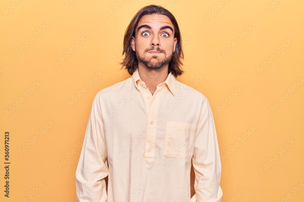 Young handsome man wearing business clothes puffing cheeks with funny face. mouth inflated with air, crazy expression.