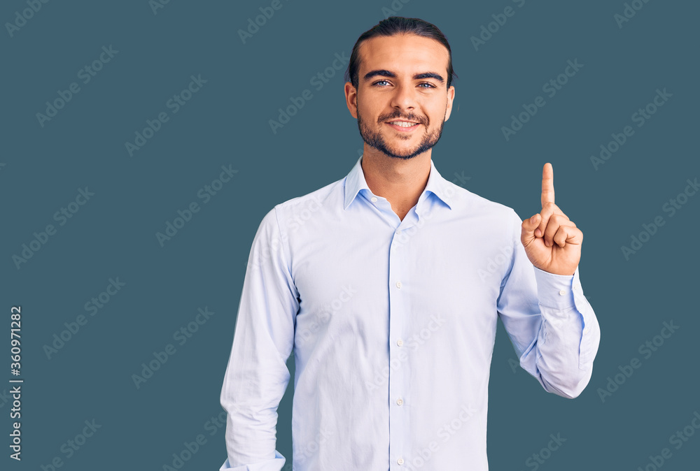 Young handsome man wearing business clothes showing and pointing up with finger number one while smiling confident and happy. Young handsome man wearing business clothes showing and pointing up with finger number one while smiling confident and happy.