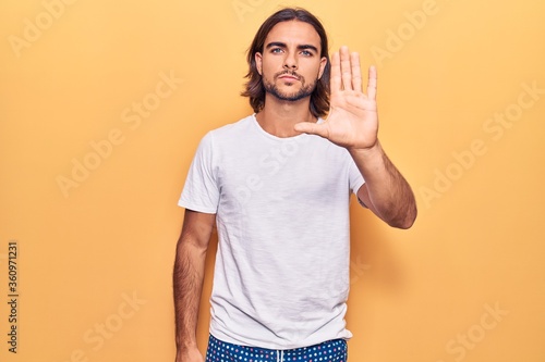 Young handsome man wearing casual clothes doing stop sing with palm of the hand. warning expression with negative and serious gesture on the face.