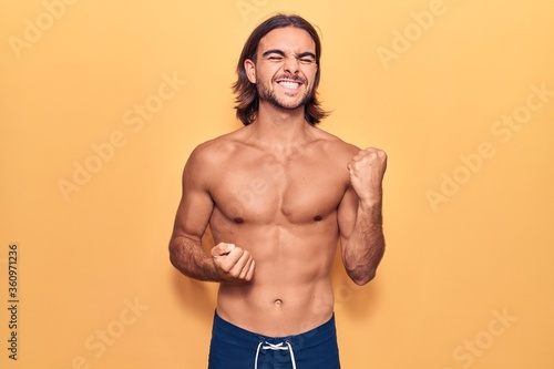 Young handsome man wearing swimwear shirtless celebrating surprised and amazed for success with arms raised and eyes closed