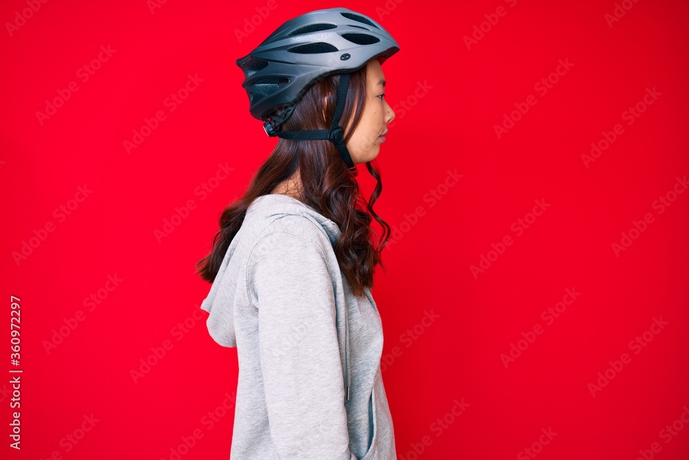Young beautiful chinese girl wearing bike helmet looking to side, relax profile pose with natural face with confident smile. Young beautiful chinese girl wearing bike helmet looking to side, relax profile pose with natural face with confident smile.